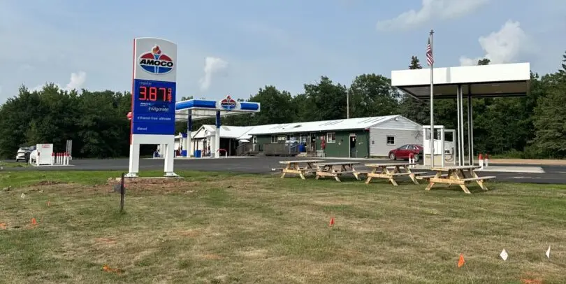 A gas station with picnic tables and a large sign.